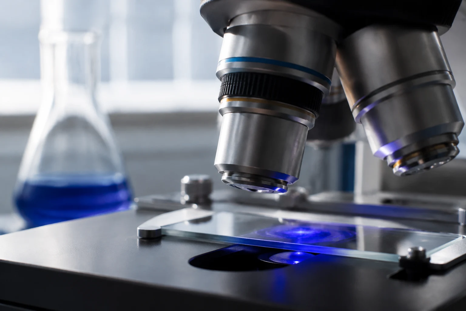 Illustrative close-up of a microscope and glassware in a laboratory
